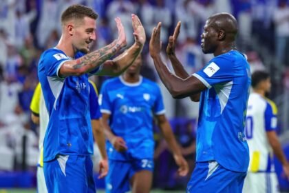 لاعبان من الهلال يرفعان أيديهما لتبادل التحية على أرض الملعب أمام المدرجات