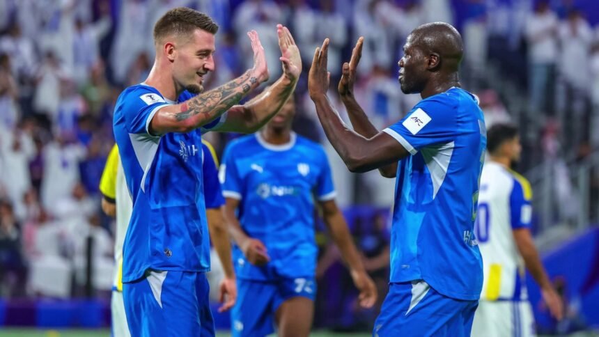 لاعبان من الهلال يرفعان أيديهما لتبادل التحية على أرض الملعب أمام المدرجات
